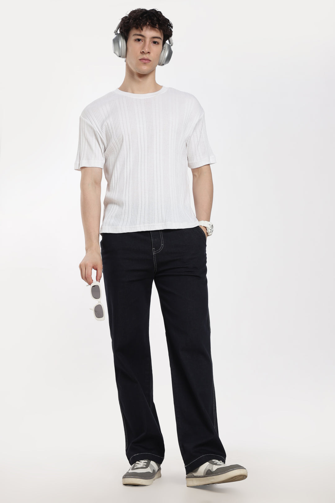 man wearing a white t-shirt, blue jogger, and headphones on a white background