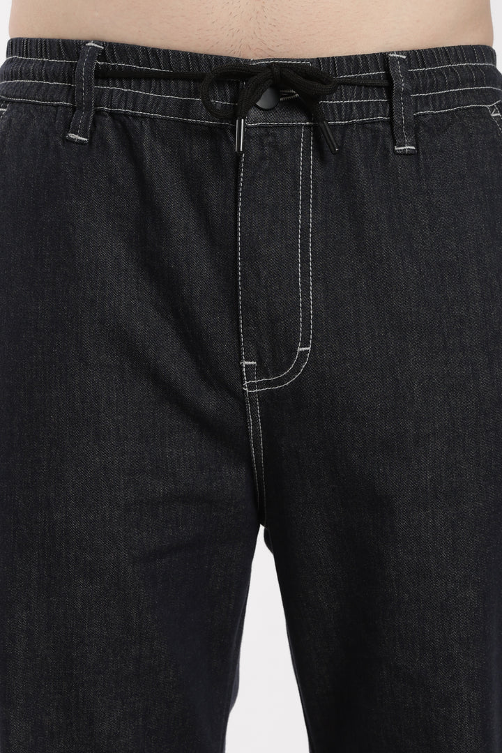 dark wash denim jogger pants with a drawstring waist on a white background