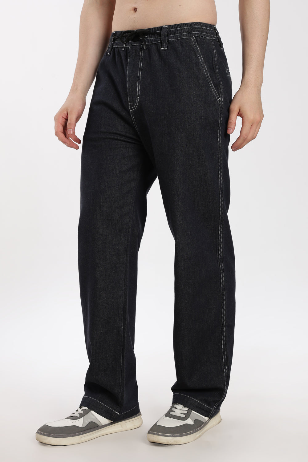 man wearing dark wash denim jogger pant on a white background