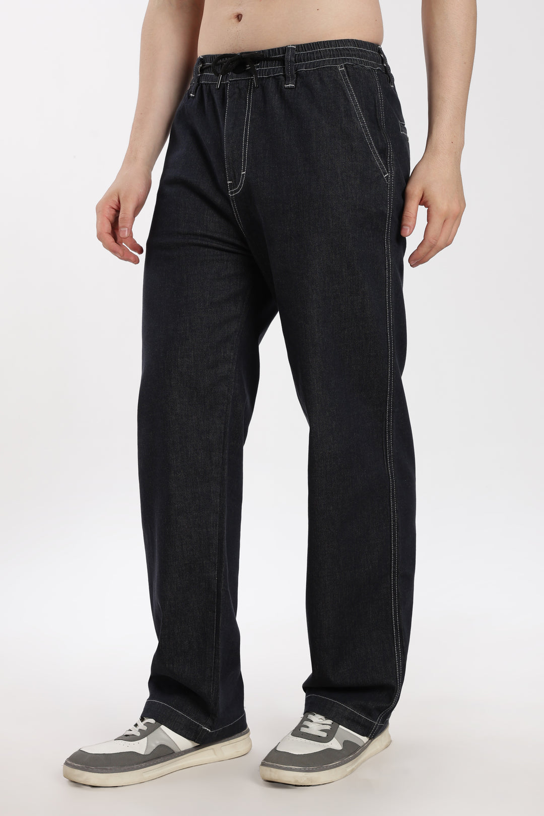 man wearing dark wash denim jogger pant on a white background