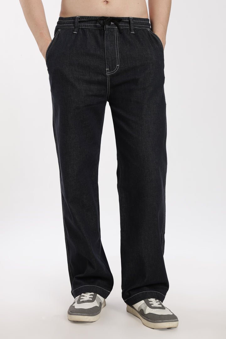 man wearing dark wash denim jogger pant on a white background