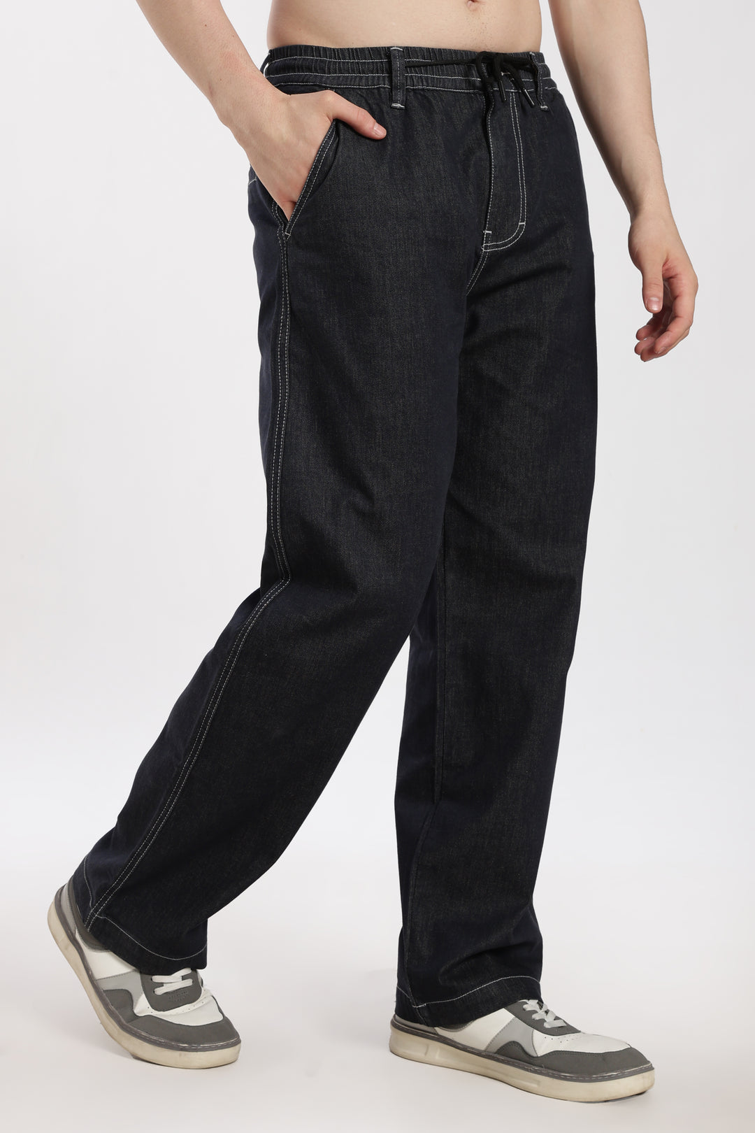man wearing dark wash denim jogger pant on a white background