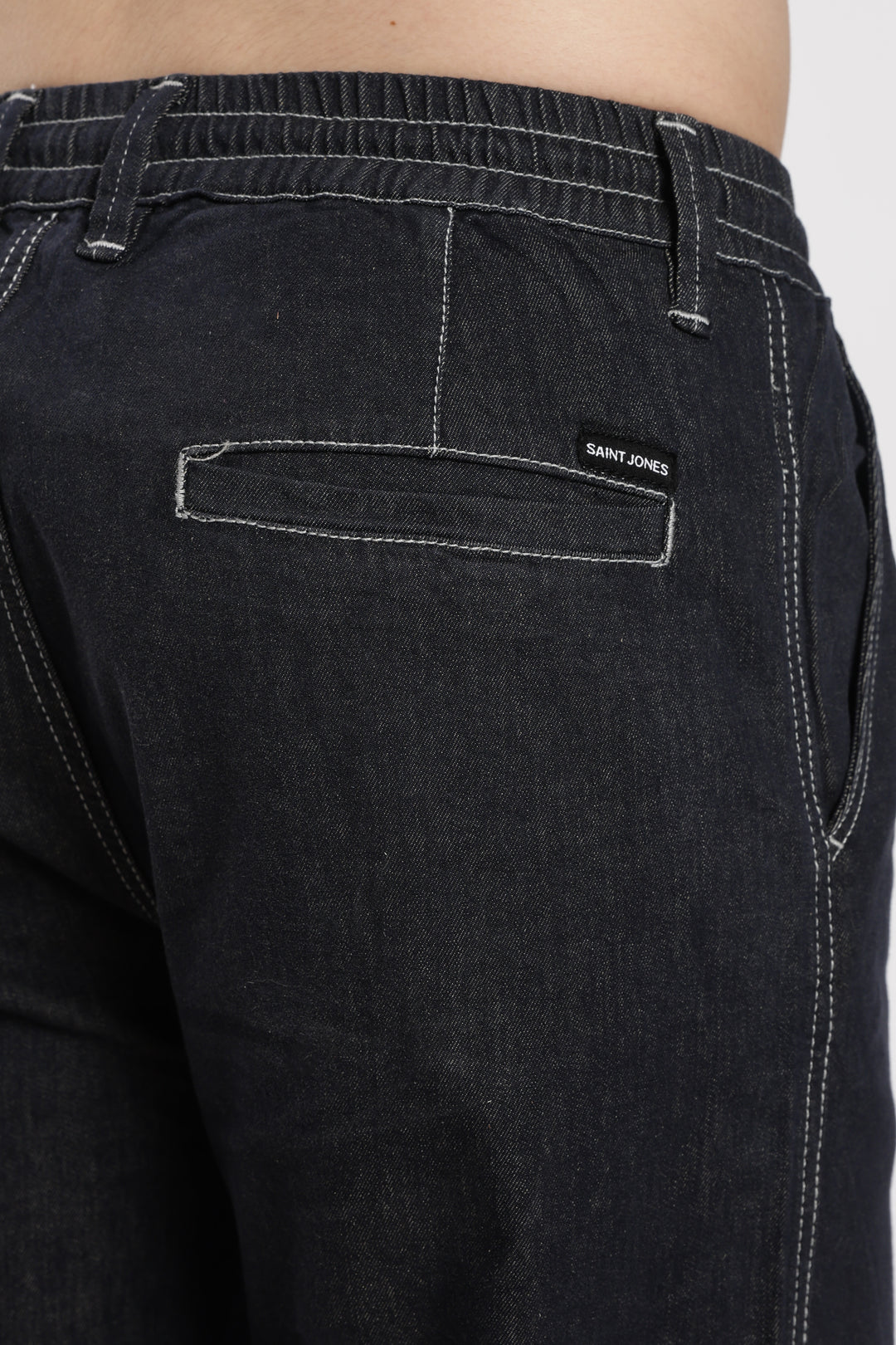 dark wash denim jogger pant with a brand saint jones on the back pocket against a white background