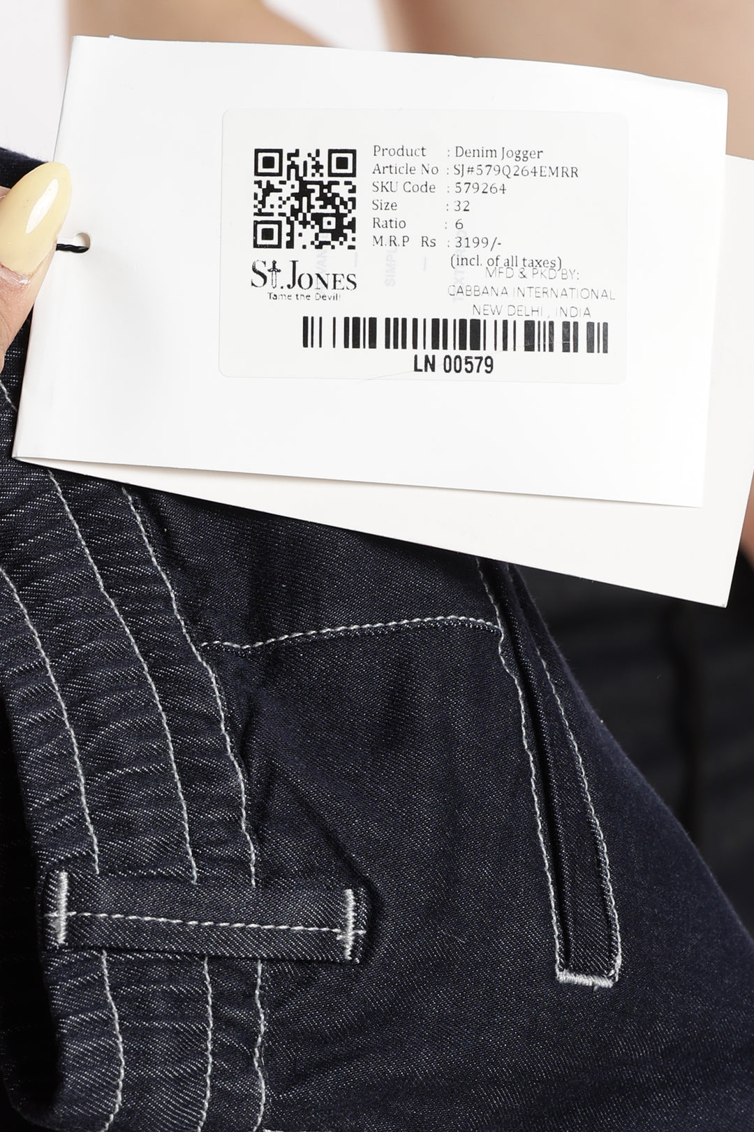 Close-up of a denim jogger pant with a label displaying a QR code and text.