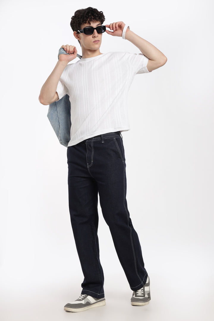 man wearing a white t-shirt, navy blue denim jogger pant, and sunglasses on a white background