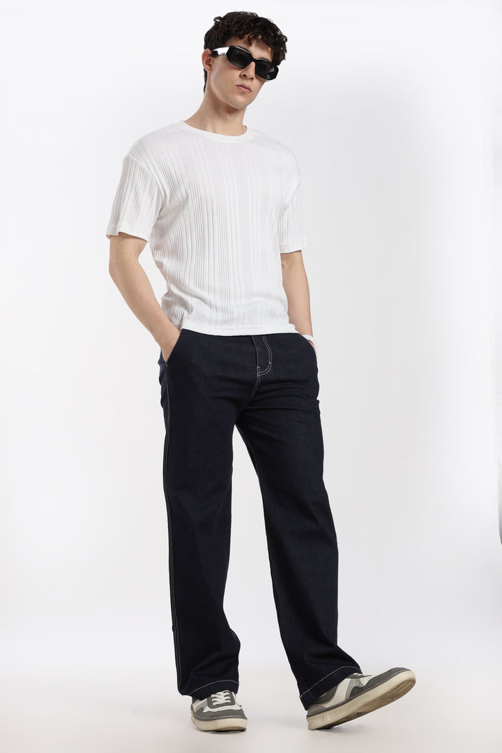 man wearing a white t-shirt and navy blue denim jogger jeans on a white background