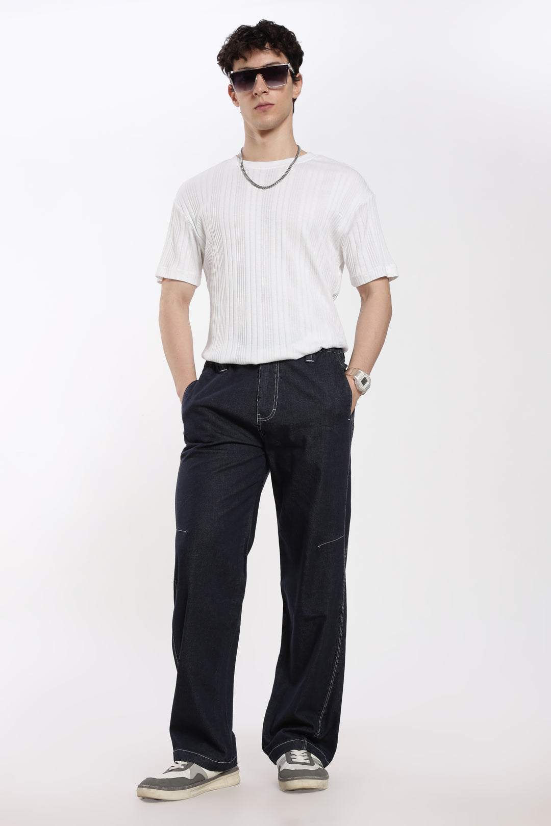 Man wearing a white t-shirt, blue denim jogger, and sunglasses on a white background