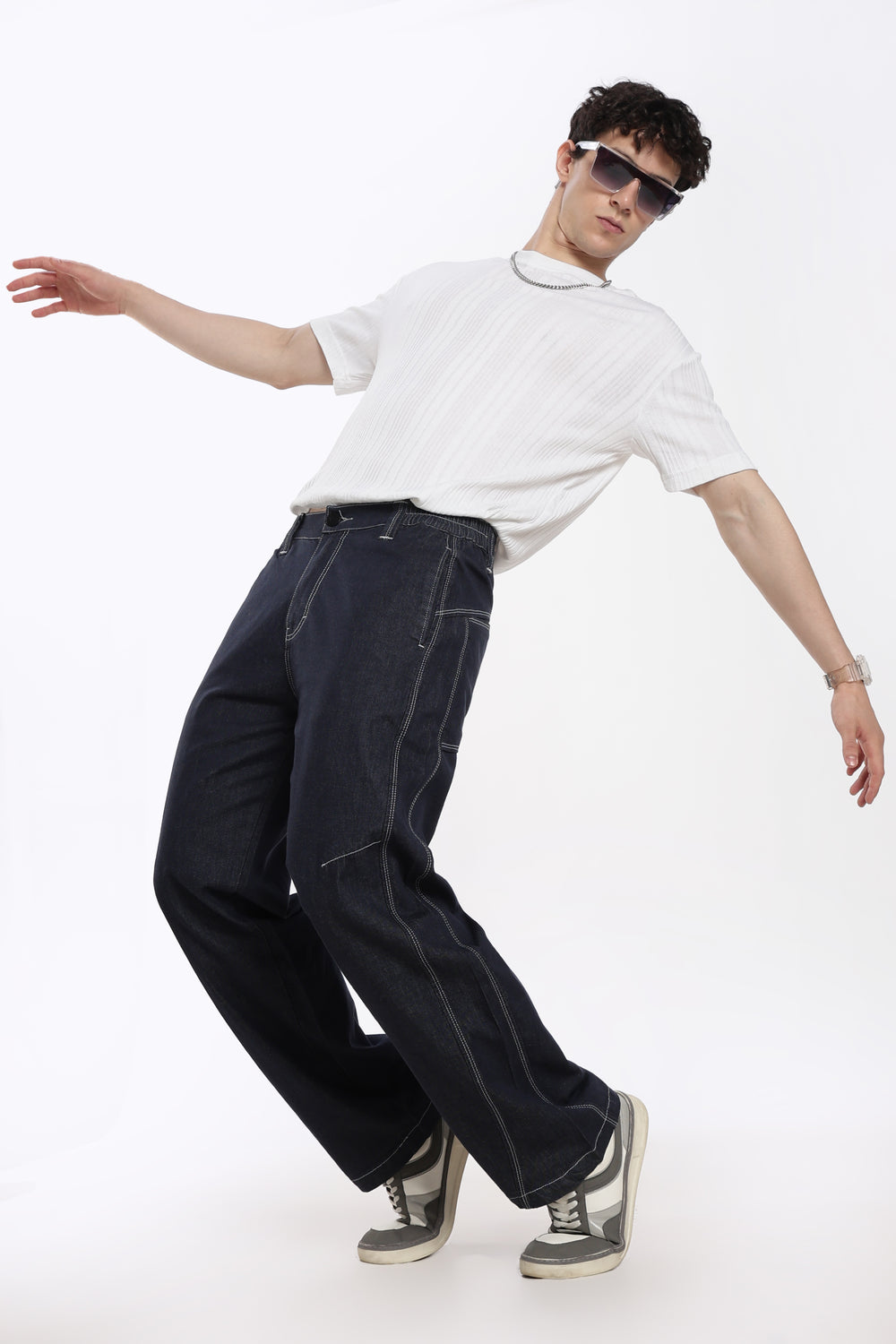 man wearing a white t-shirt, blue denim jogger, and sunglasses on a white background