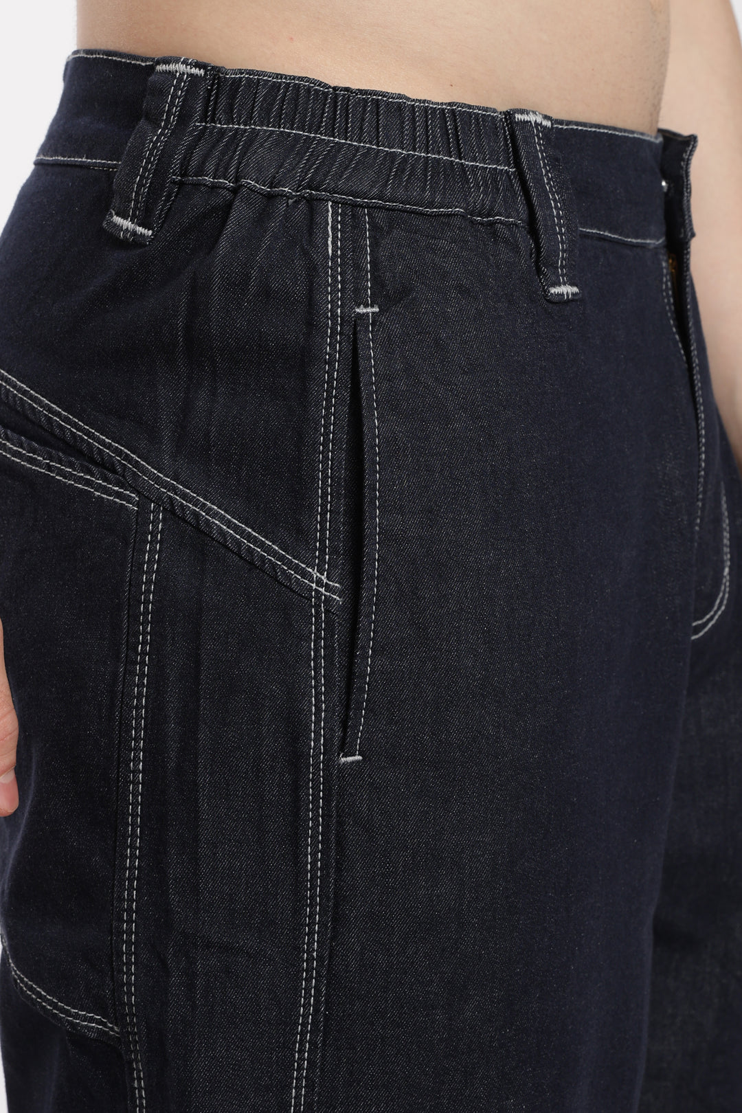 Close-up of blue denim jogger with white stitching on a plain background
