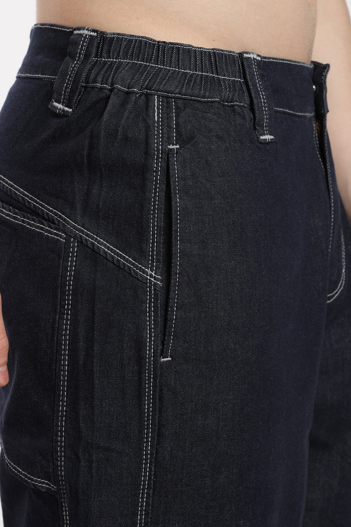 Close-up of blue denim jogger with white stitching on a plain background