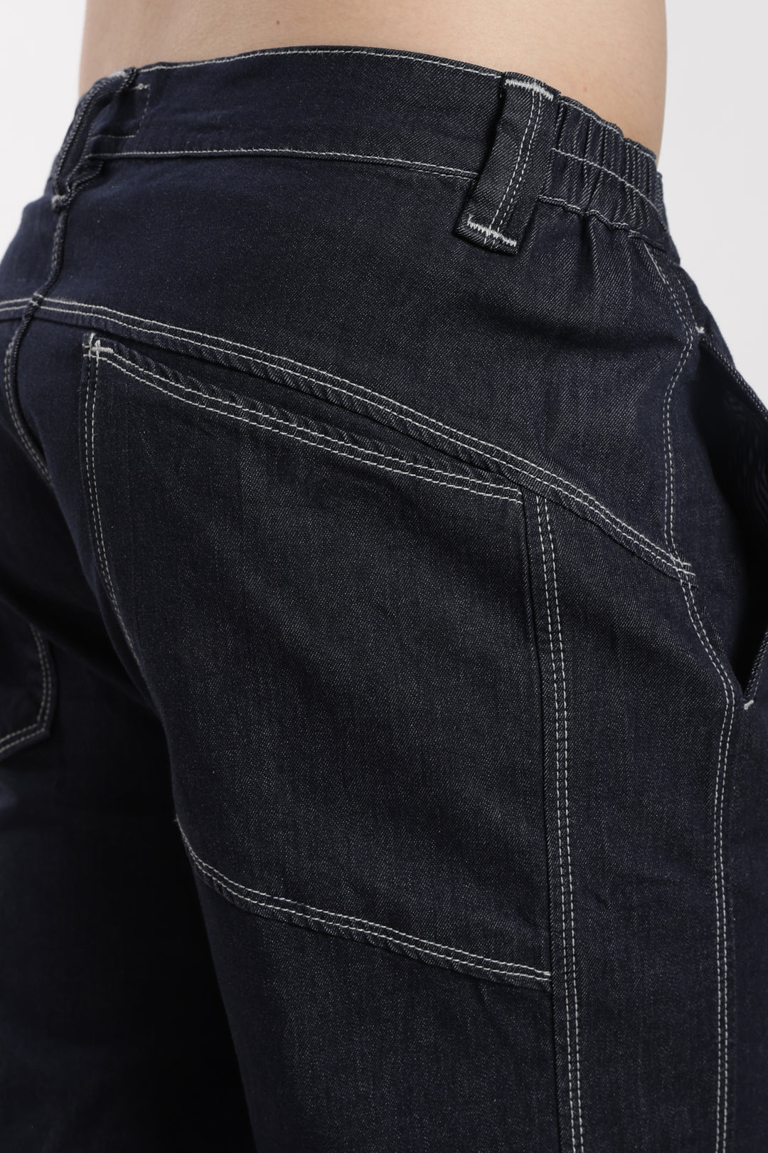 Close-up of blue denim jogger with visible stitching on a white background