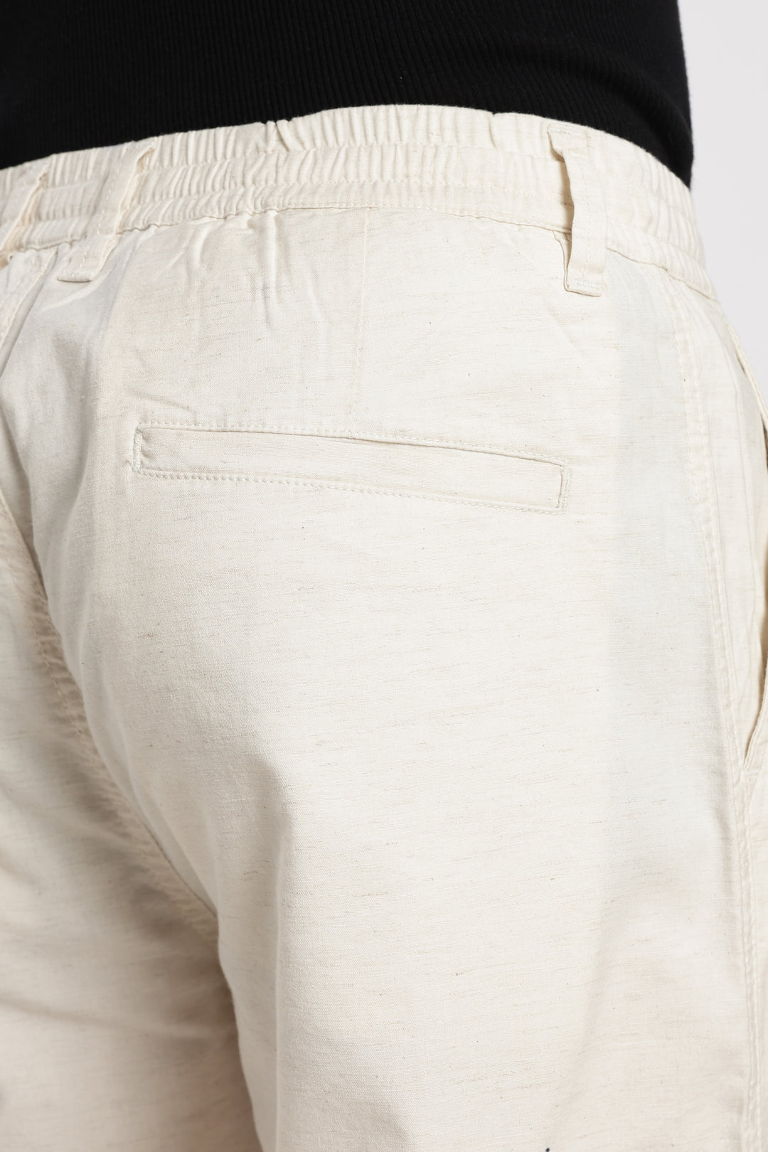 cream linen pants with a black top on a white background