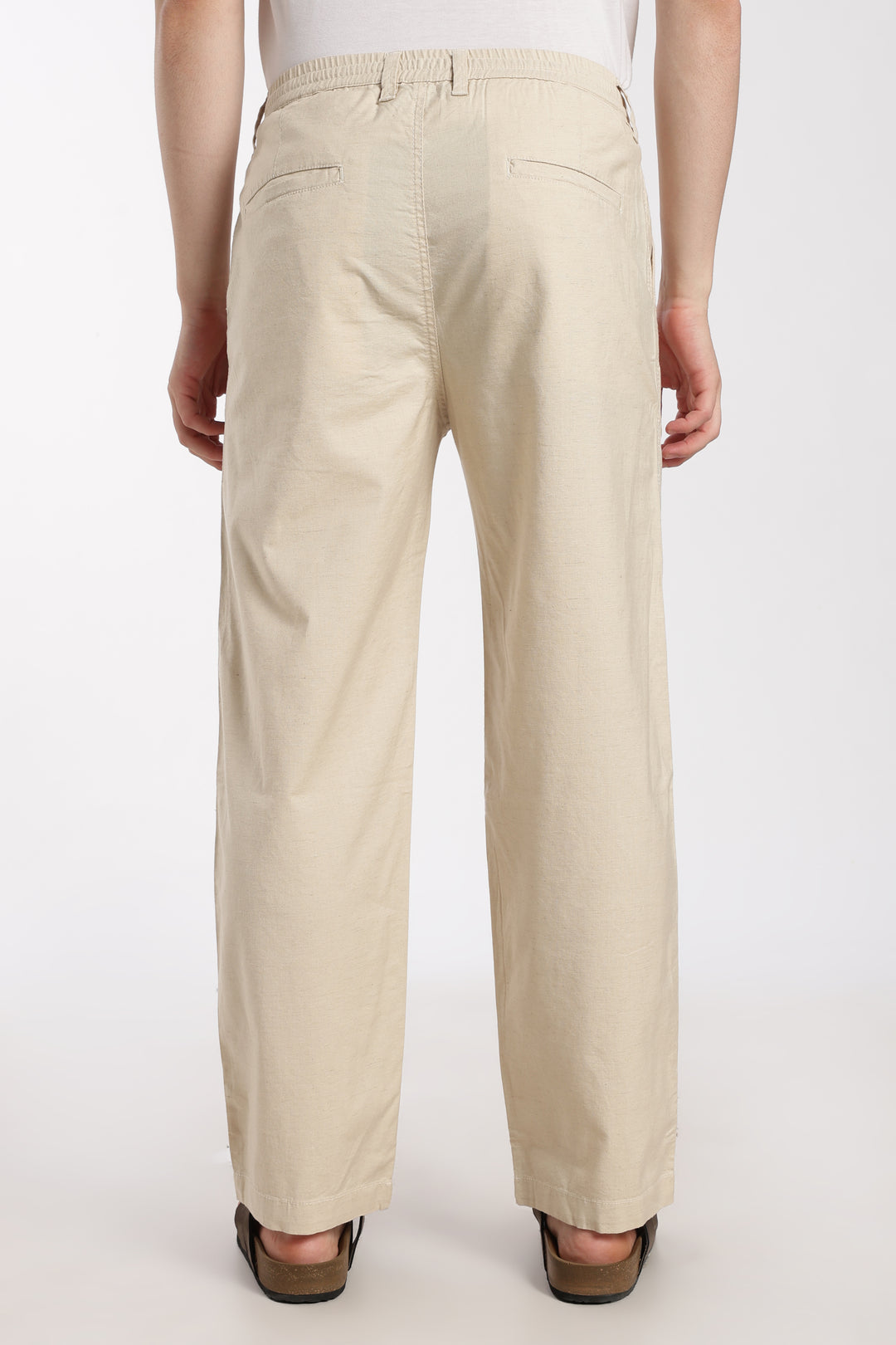 Beige linen pants worn by a man on a white background