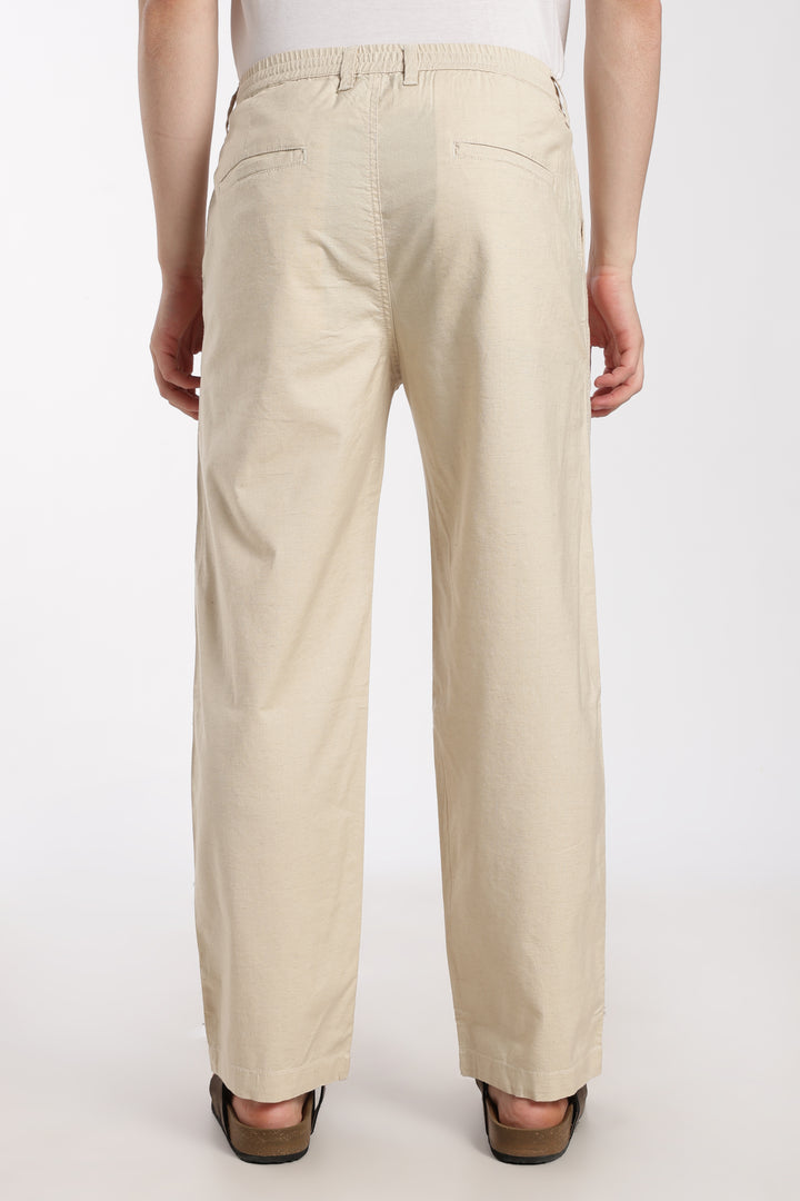 Beige linen pants worn by a man on a white background