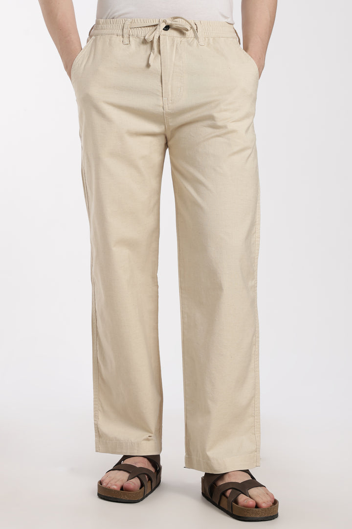 Beige linen pants worn by a man on a white background