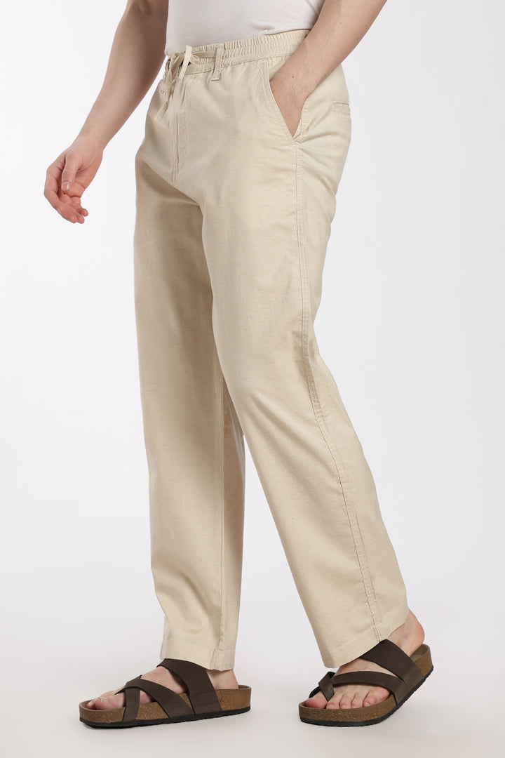 Beige linen pants worn by a man on a white background