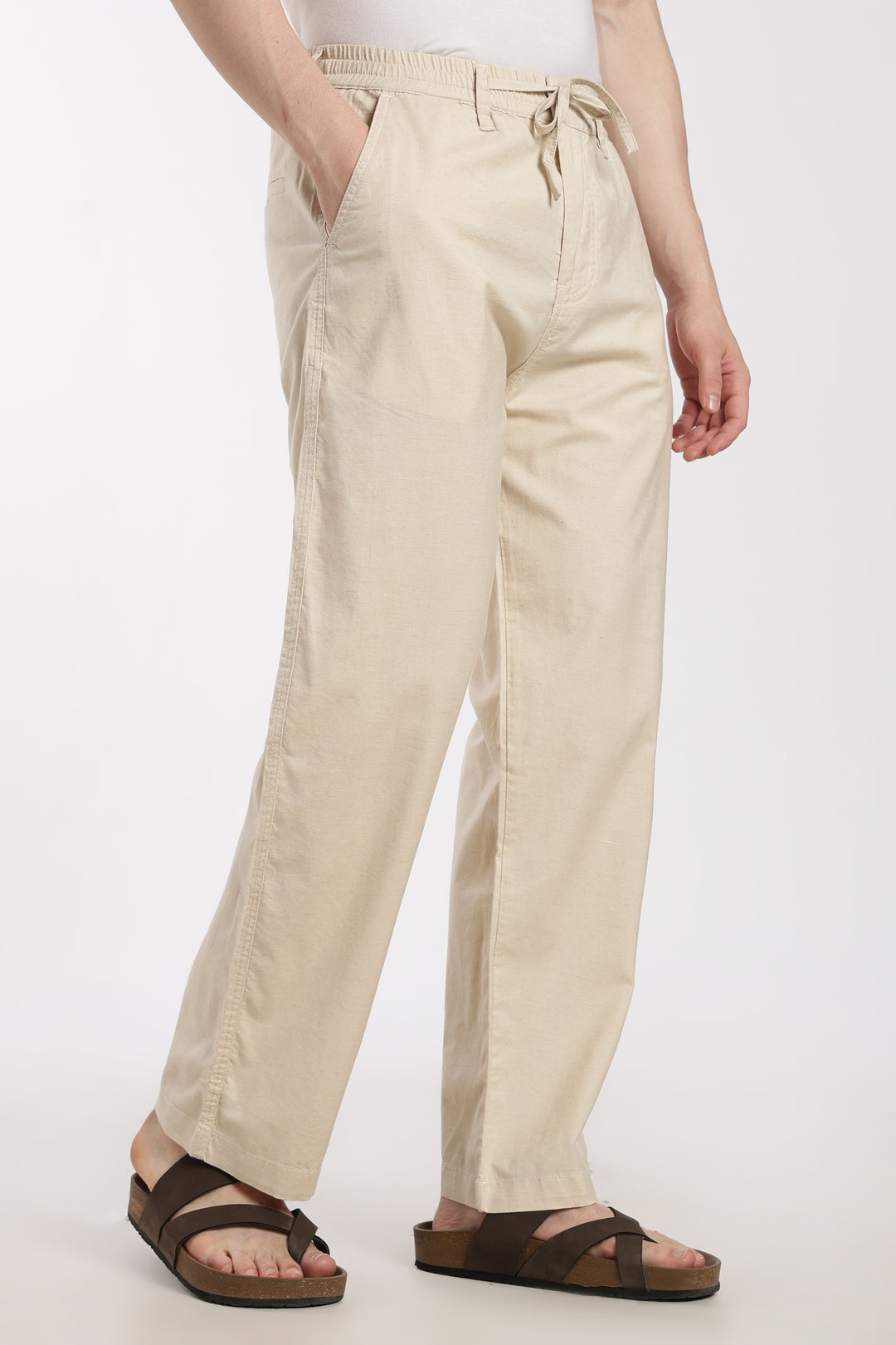 Beige linen pants worn by a man on a white background