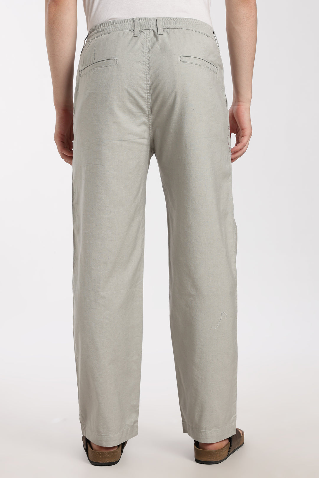 Light gray linen pants worn by a man on a white background