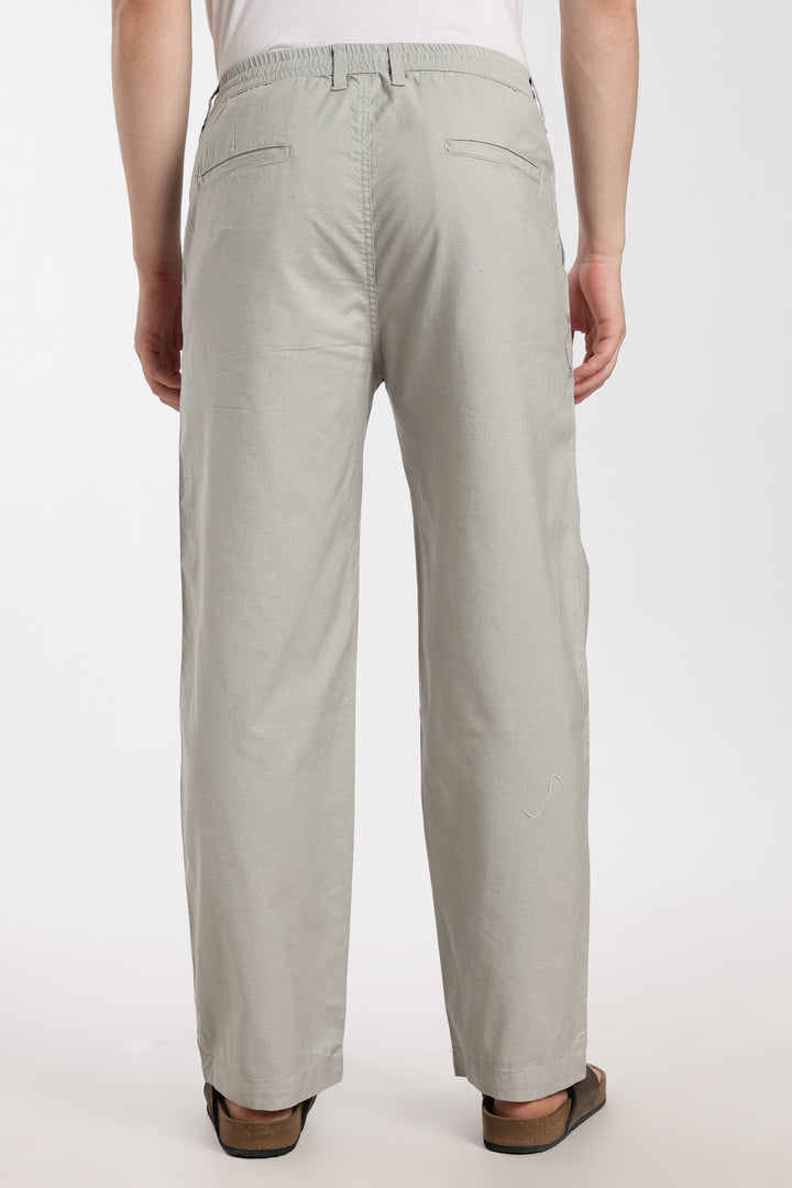 Light gray linen pants worn by a man on a white background