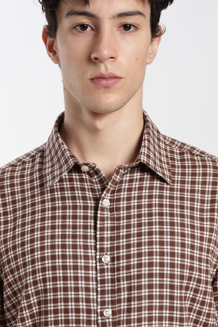Man wearing a brown and white checkered half sleeve shirt against a plain background