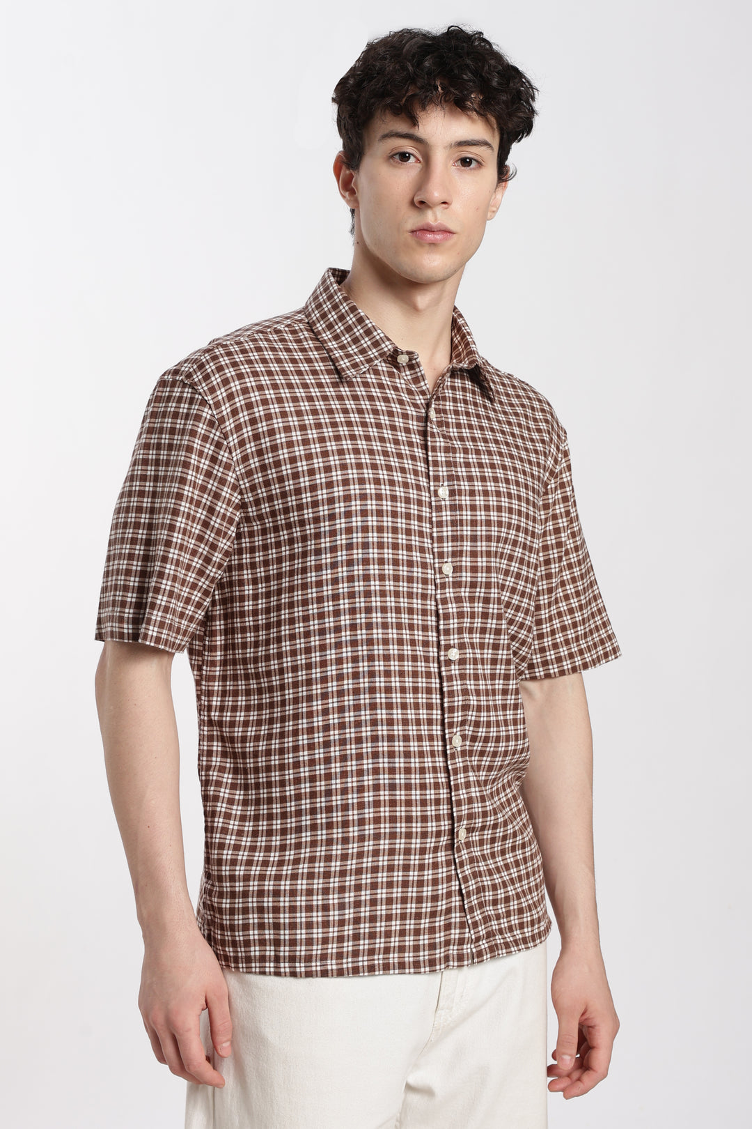 Man wearing a brown checkered half sleeve shirt on a white background