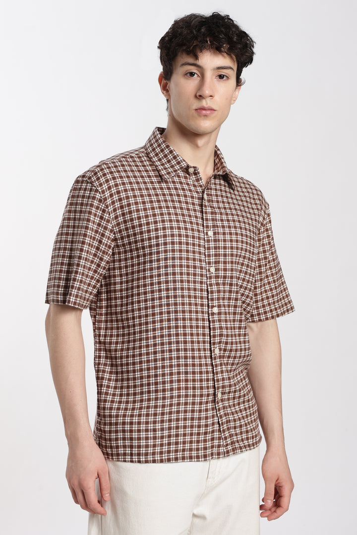 Man wearing a brown checkered half sleeve shirt on a white background