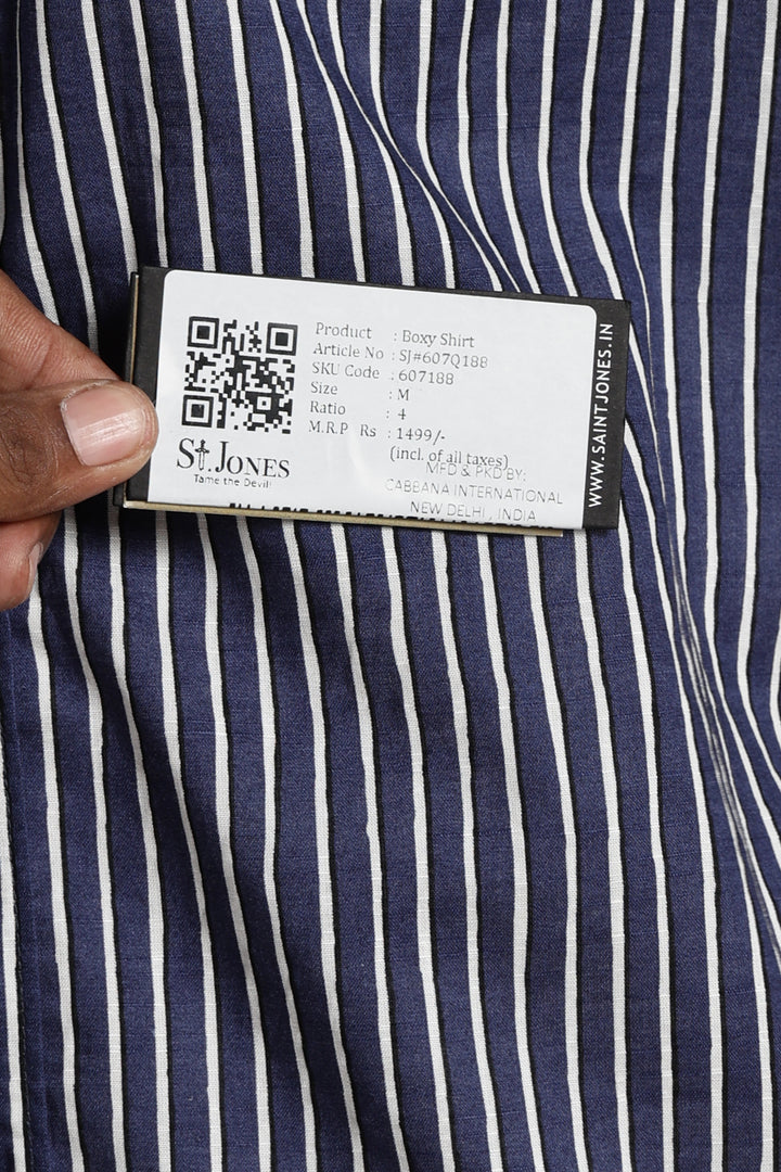 Close-up of a navy and white striped half sleeve shirt with a brand label held by a hand.