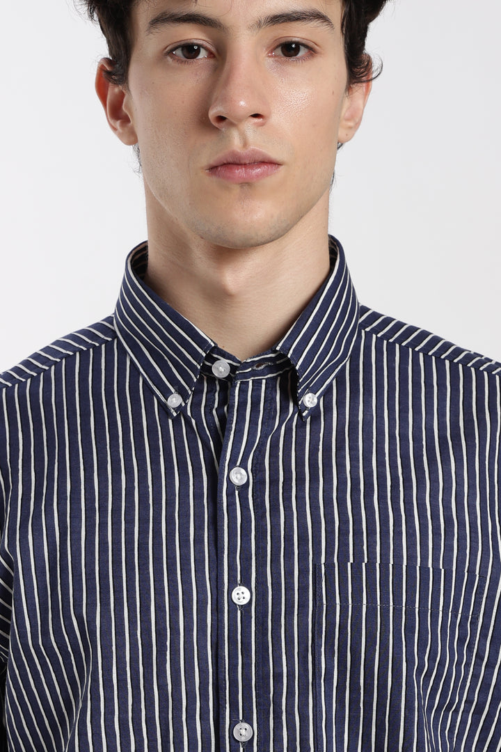 Man wearing a navy blue and white striped half sleeve shirt on a white background
