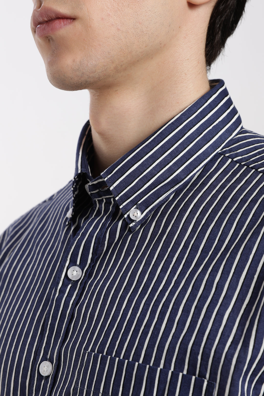 Navy and white striped half sleeve shirt worn by a man on a plain background