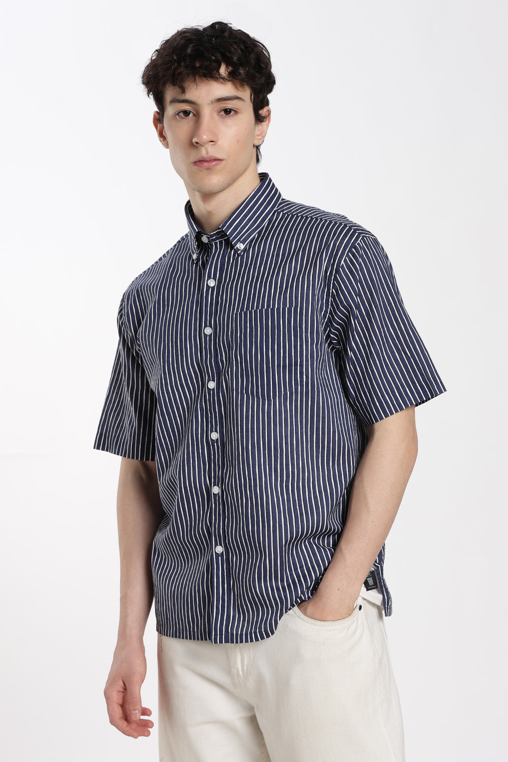Man wearing a striped half sleeve shirt and white pants on a white background