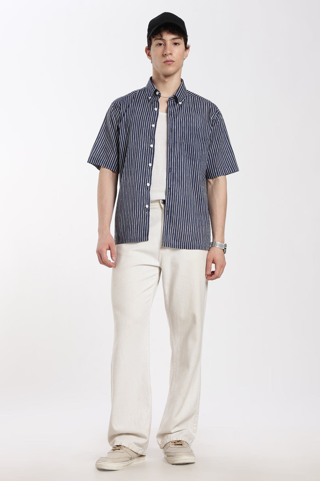 Man wearing a blue striped half sleeve shirt and white pants on a white background