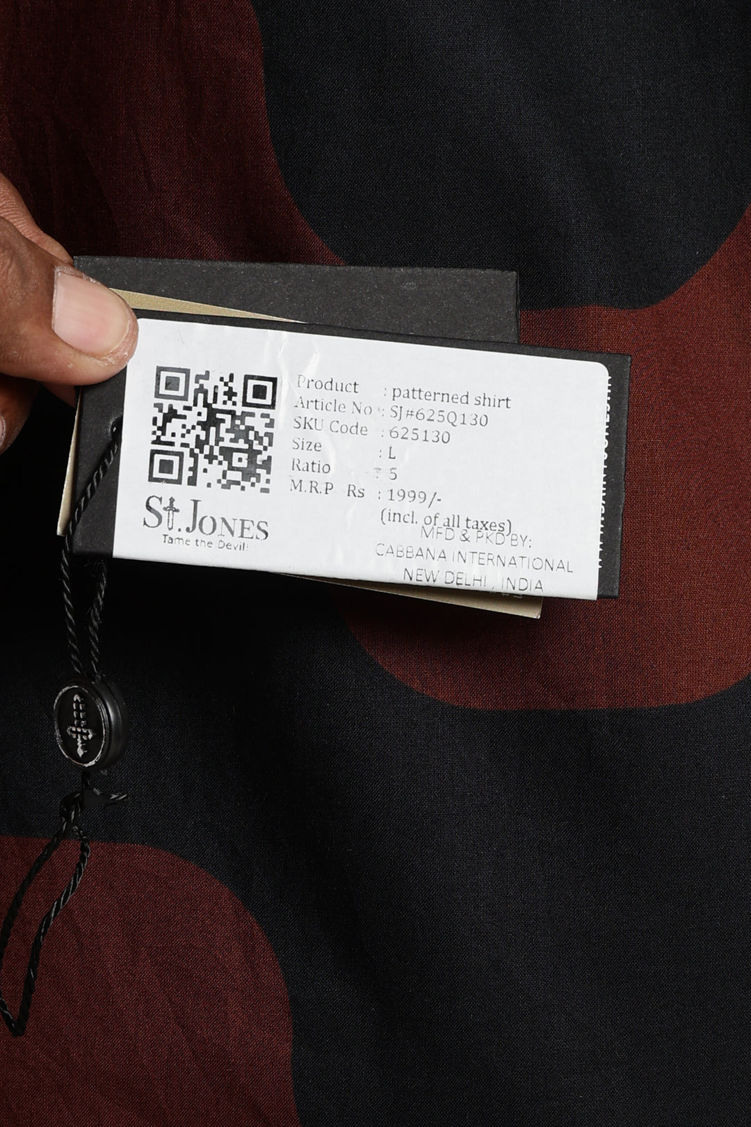 Product tag with QR code and saint jones branding held by a person