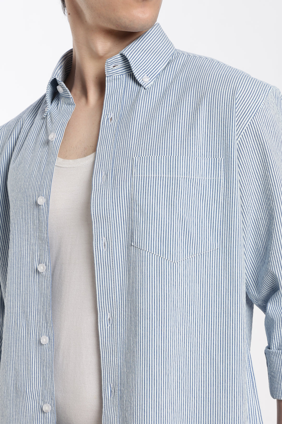 Man wearing a blue and white striped linen shirt  on a light gray background