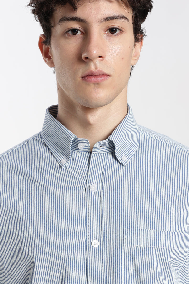 Man wearing a blue and white striped linen shirt against a plain background