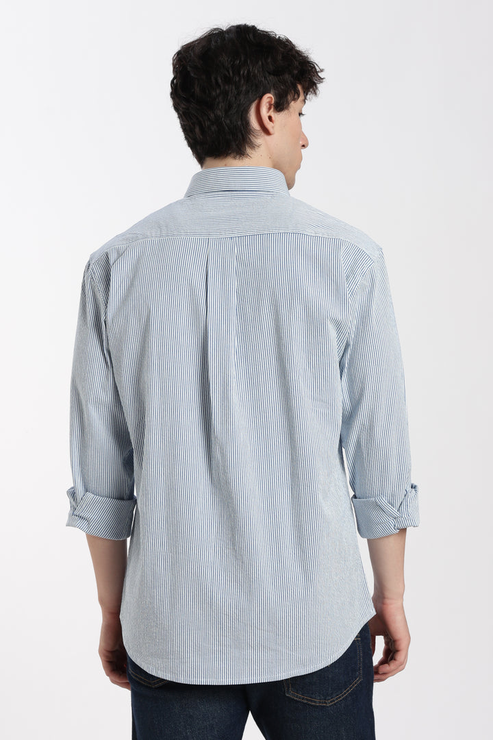 man wearing a blue striped linen shirt from behind on a white background