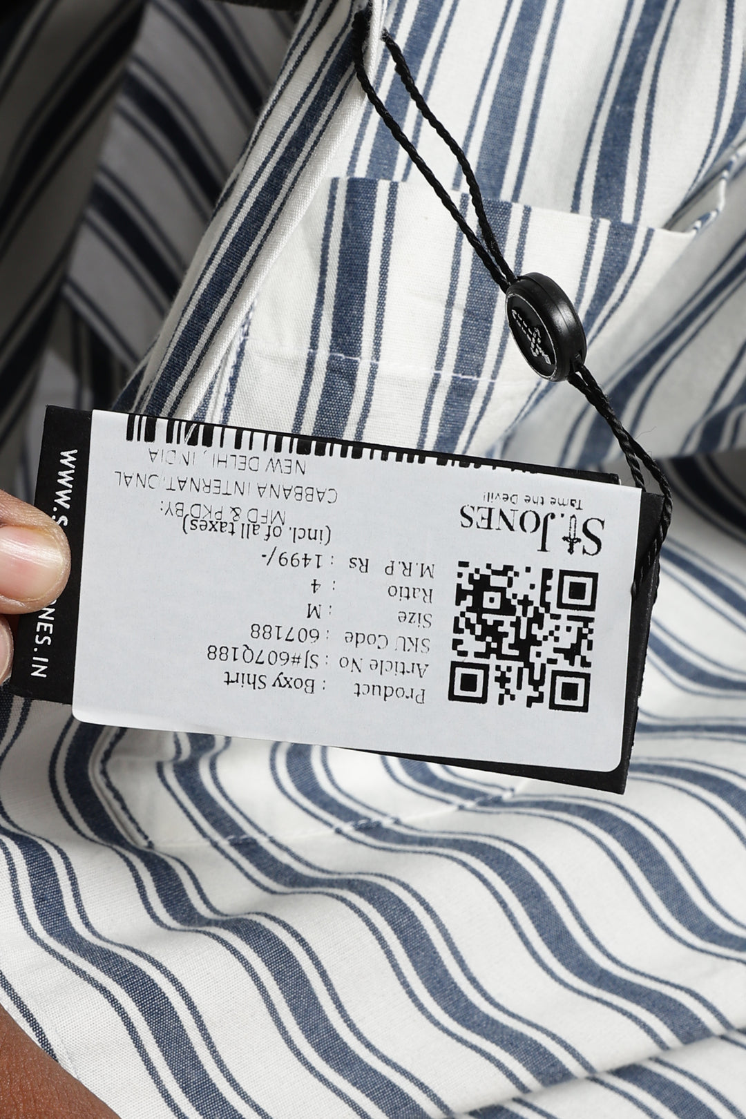 Close-up of a clothing tag with a QR code on a striped fabric background