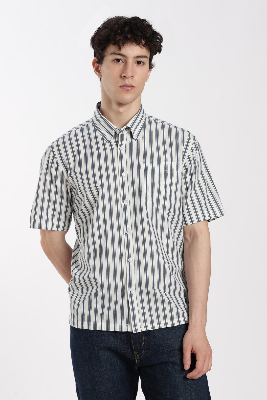 Man wearing a striped half sleeve shirt and dark jeans on a white background