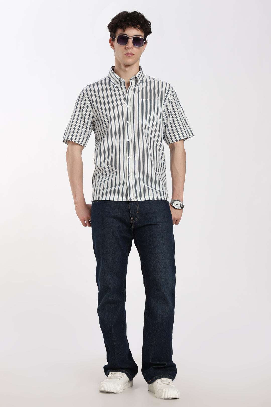 Man wearing a striped half sleeve shirt and dark jeans on a white background