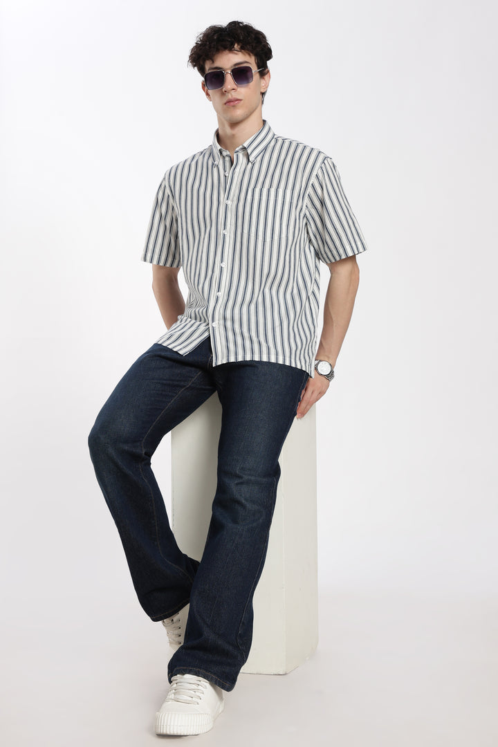 Man wearing a striped half sleeve shirt and dark pants on a white background