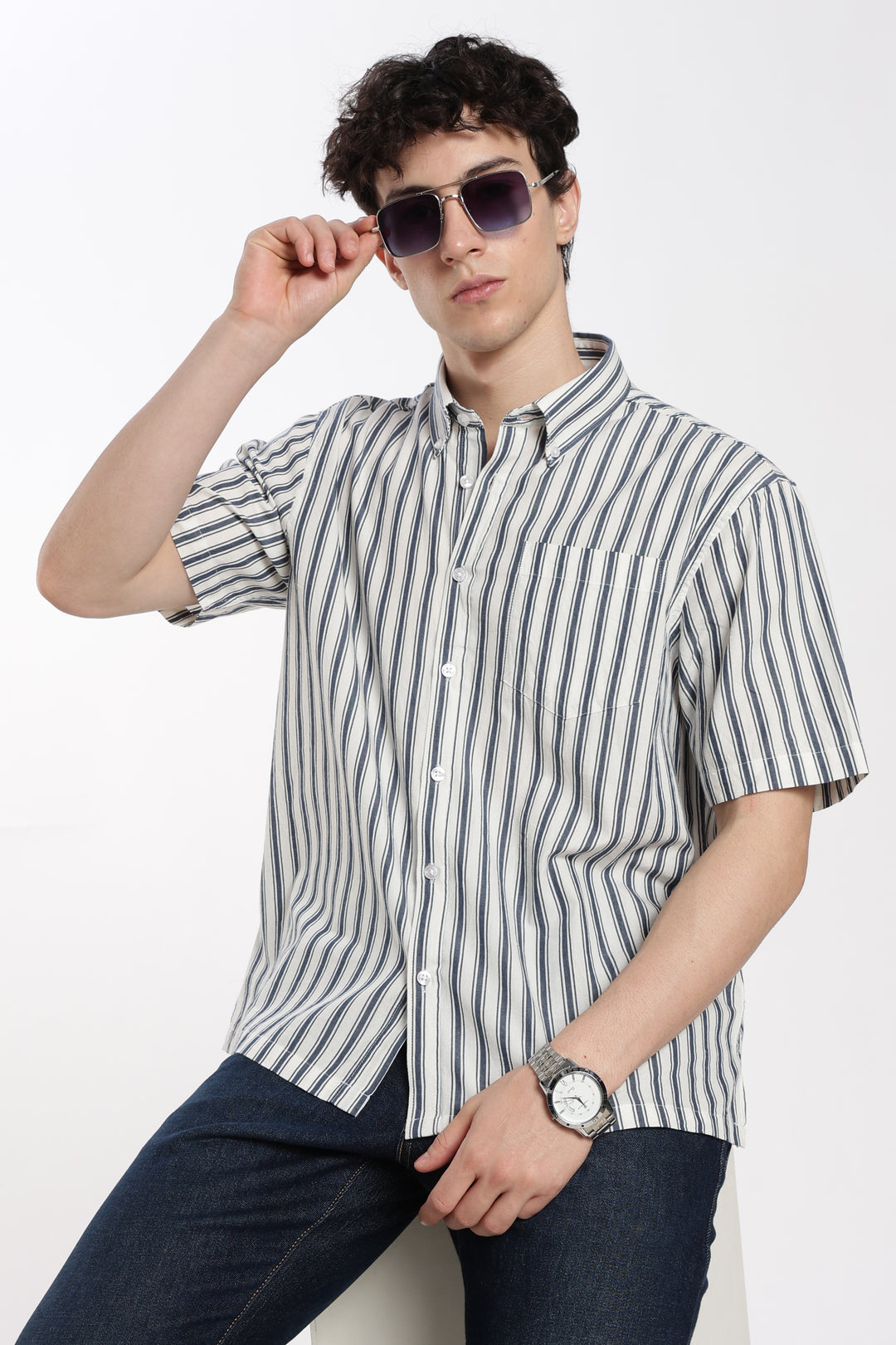 Man wearing a striped half sleeve shirt and sunglasses on a white background