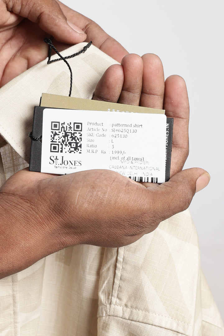 Hand holding a clothing label with a QR code and saint jones brand name on a plain background