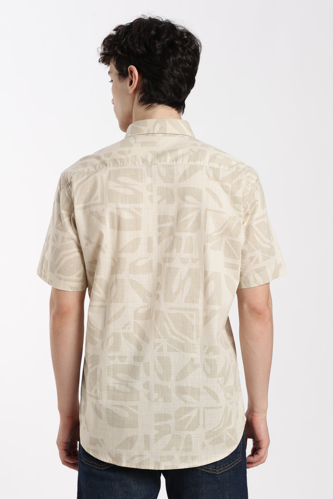 Man wearing a beige patterned half sleeve shirt on a white background