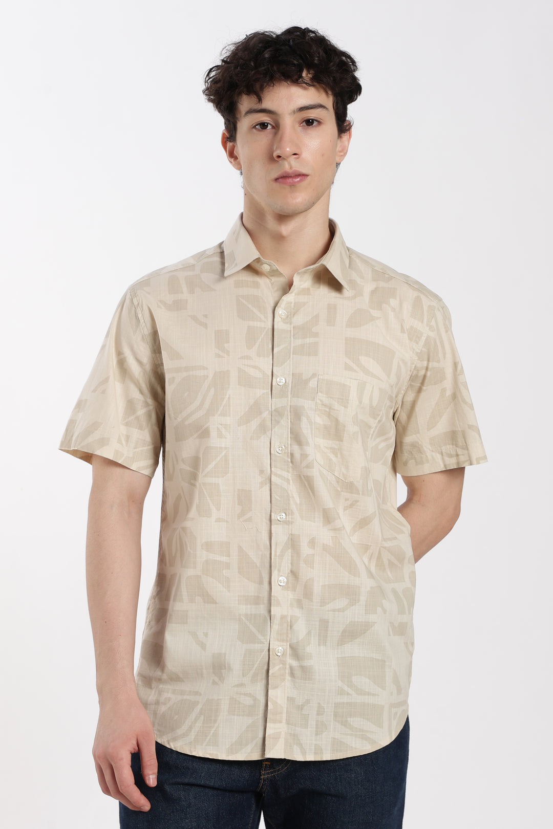 Man wearing a beige patterned half sleeve shirt on a white background