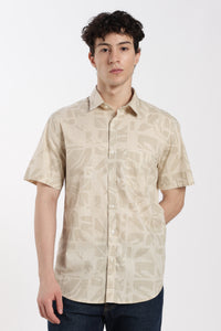 Man wearing a beige patterned half sleeve shirt on a white background