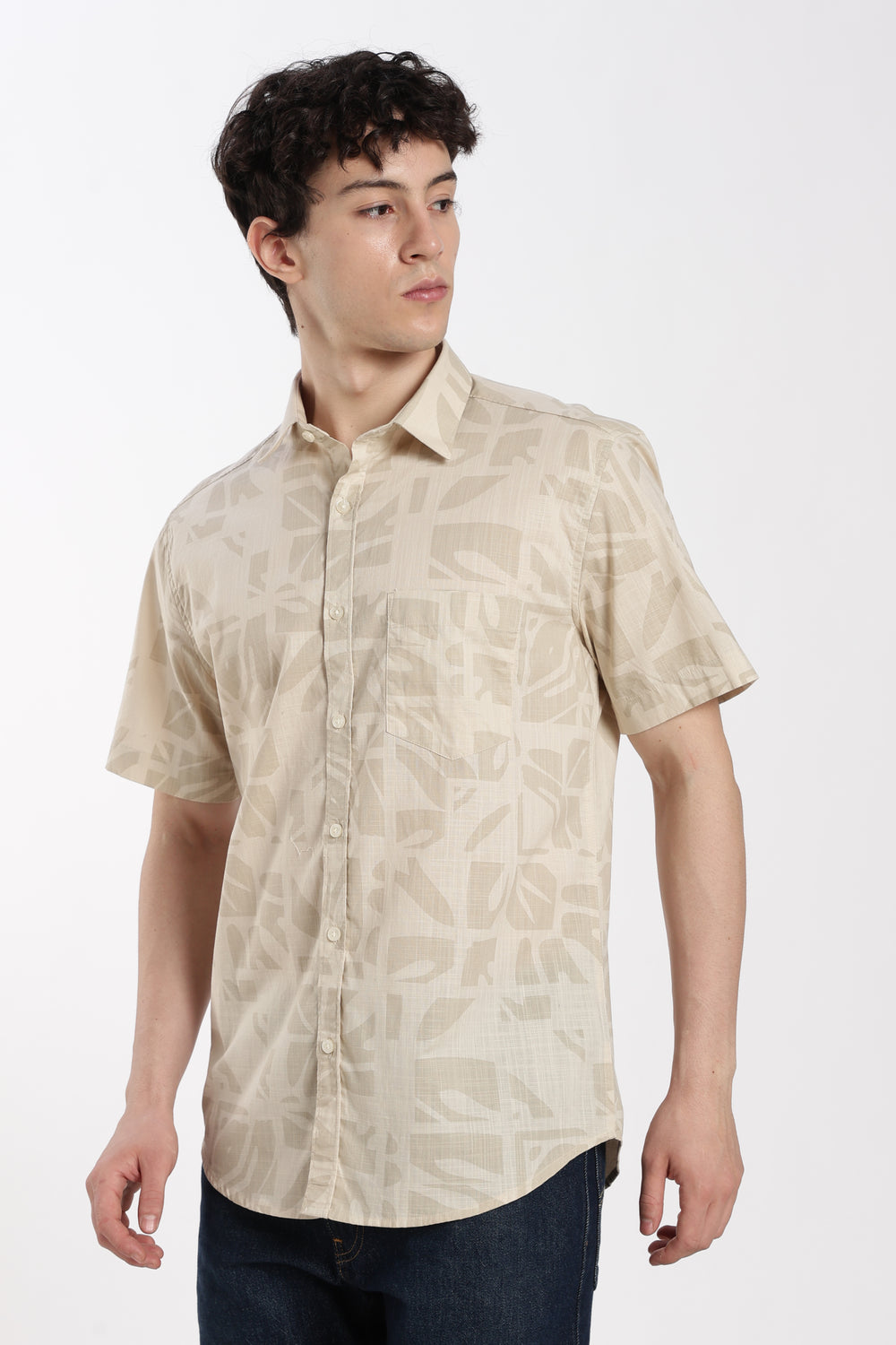Man wearing a beige patterned half sleeve shirt on a white background