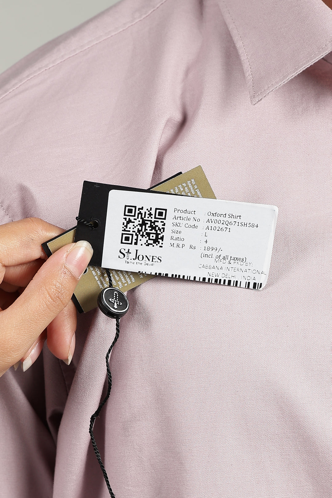 man holding a garment tag with a QR code and product information on a mutepink shirt.