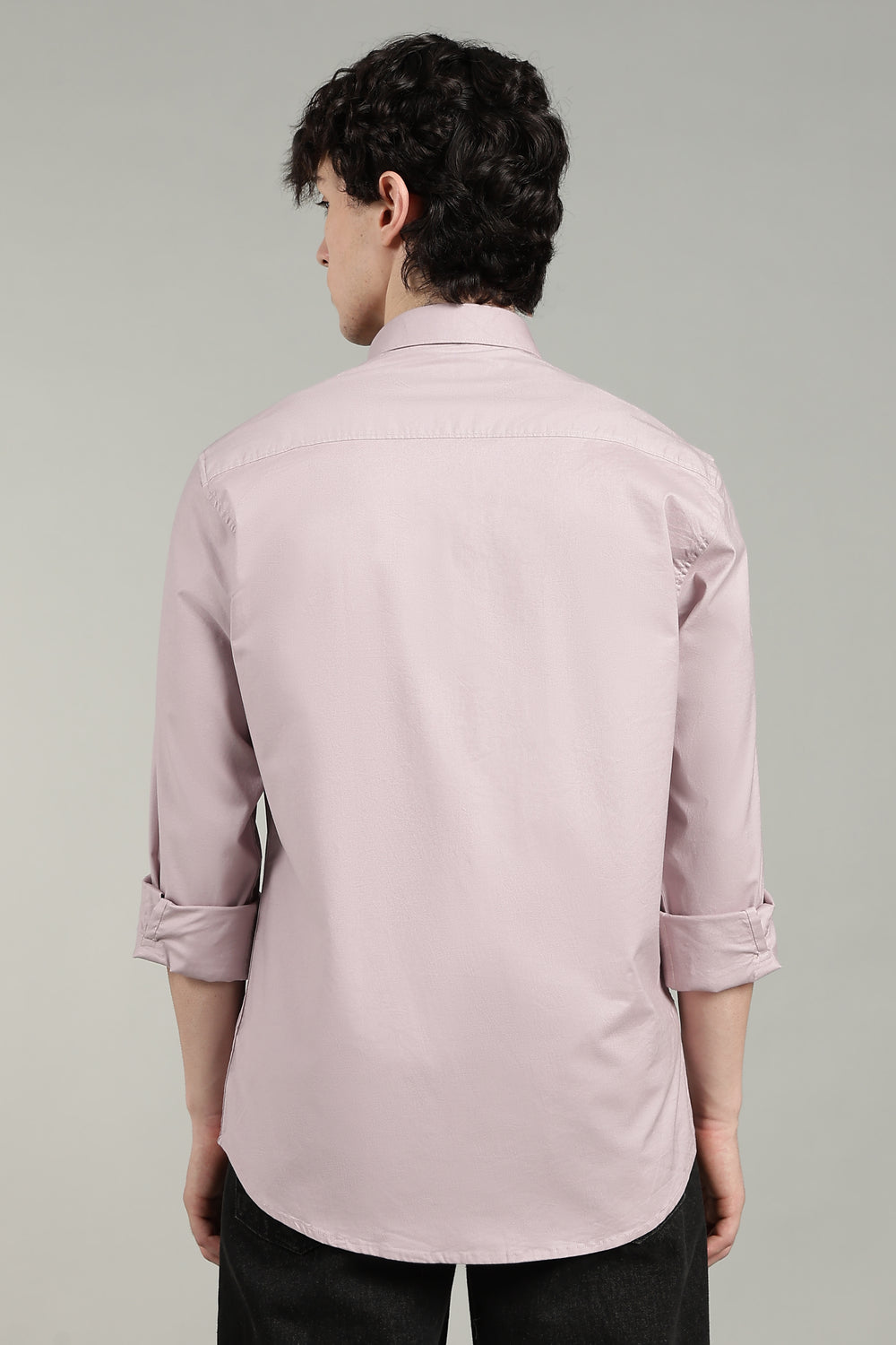 man wearing a mute pink shirt against a gray background
