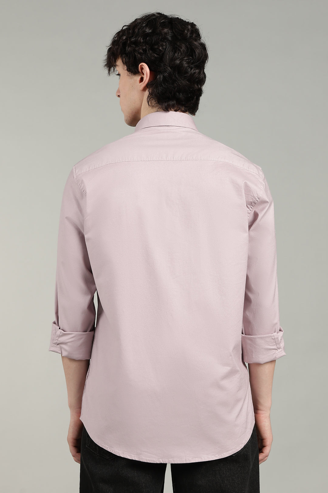 man wearing a mute pink shirt against a gray background