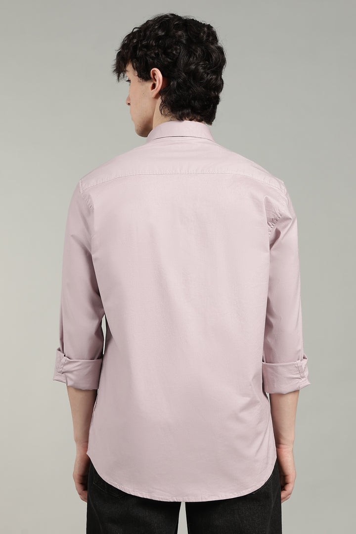 man wearing a mute pink shirt against a gray background