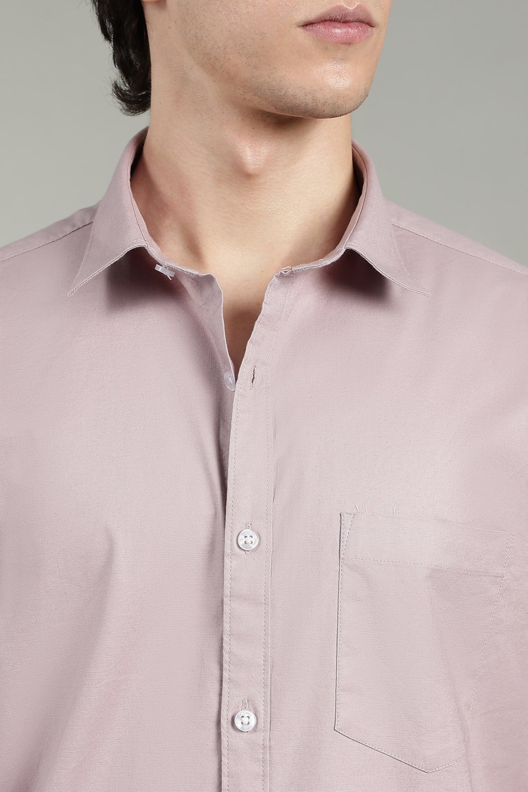 Close-up of a mute pink shirt worn by a man on a gray background